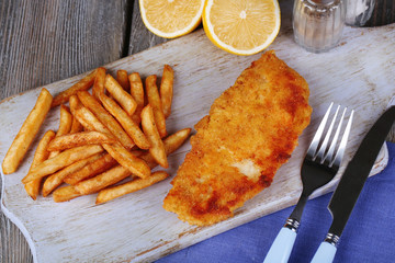 Breaded fried fish fillet and potatoes with sliced lemon and