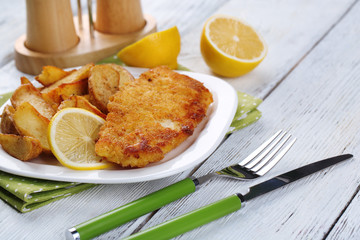 Breaded fried fish fillet and potatoes with sliced lemon