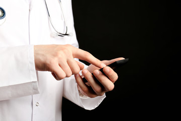 Doctor working with mobile phone on black background