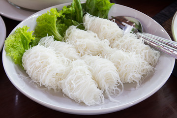 Close up of white rice noodles on a white plate.