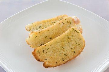 Garlic and herb bread on white plate.
