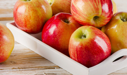 Fresh red apples  in white box on a wooden table