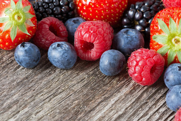 assorted fresh juicy berries on wooden background, horizontal