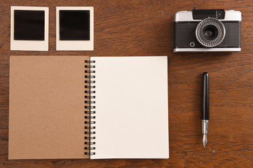 Blank notebook with pen, photo frames and camera