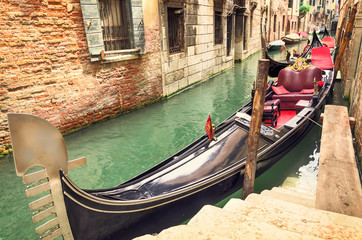 Fototapeta na wymiar Small canal with parked gondola in Venice, Italy