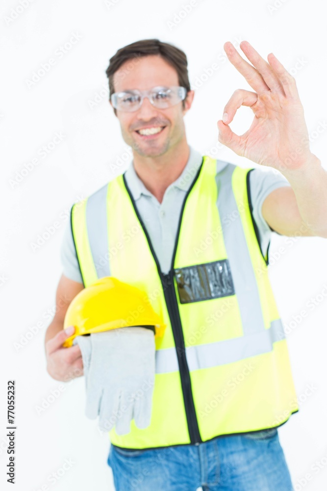 Poster carpenter holding gloves and hardhat while gesturing ok