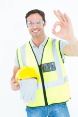 Carpenter holding gloves and hardhat while gesturing OK