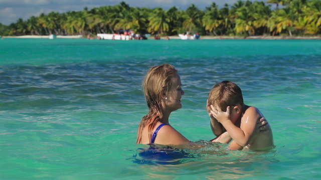 Mother and son playing in clear sea water