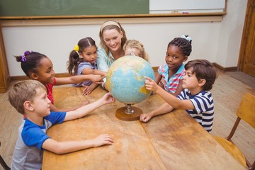 Fototapeta premium Cute pupils and teacher in classroom with globe