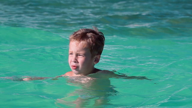 Little boy bathing in clear blue sea