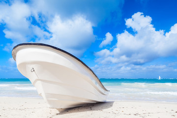 White pleasure motor boat lays on sandy beach