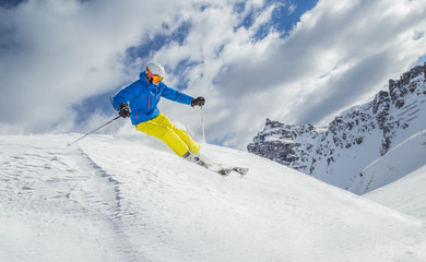 Skier skiing downhill in high mountains