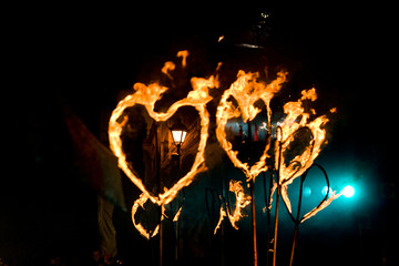 Evening street performance with fiery torches in the form of hea