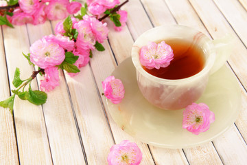 Beautiful fruit blossom with cup of tea on table close-up