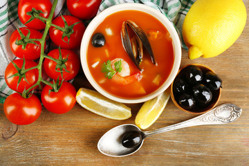 Tasty soup with shrimps, mussels, tomatoes and black olives in