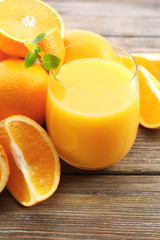 Glass of orange juice and slices on wooden table background