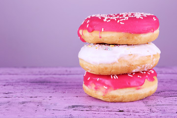 Delicious donuts with icing on table on bright background