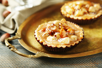 Mini cakes with nuts on napkin on wooden background