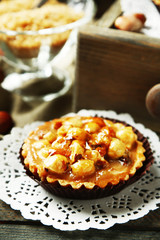 Mini cakes with nuts on napkin on wooden background