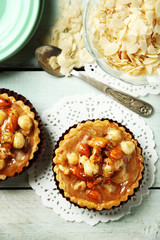 Mini cakes with nuts on lace doily on color wooden background