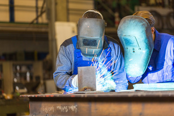 Two steel construction workers welding metal - obrazy, fototapety, plakaty