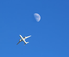 Jet plane and the Moon against a blue sky