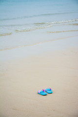 Fototapeta na wymiar Beach sandals or tongs on a sandy beach