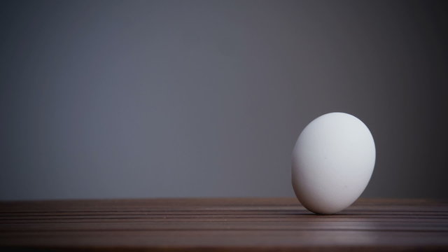 An egg is rolling across the table. Slow motion