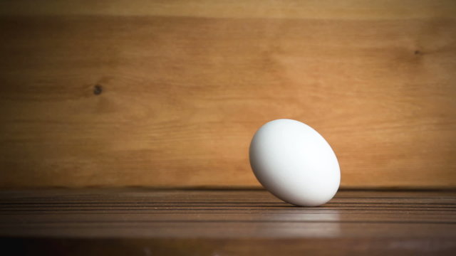 An egg is rolling across the table. Slow motion