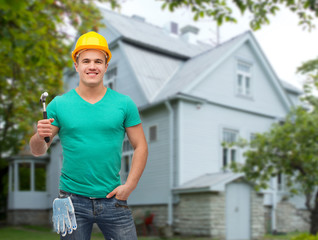 smiling manual worker in helmet with hammer