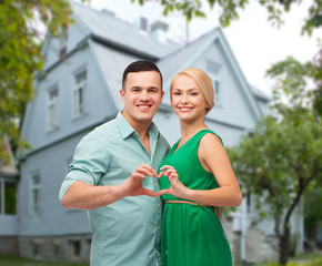 Naklejka premium smiling couple and showing heart shape gesture