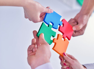 Group of business people assembling jigsaw puzzle and represent
