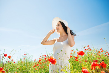 smiling young woman in straw hat on poppy field