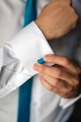 Man's hands closeup fixing his blue cufflinks