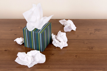 Box of  tissue box with used crumpled kleenex style white tissues on desk or table