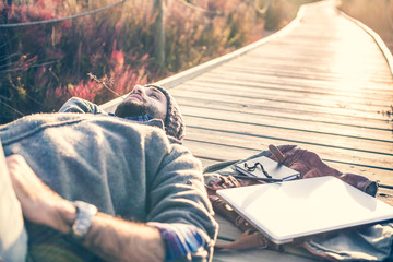 urban man lying on a catwalk in the field enjoying nature - 77092672