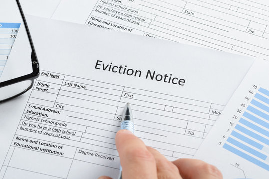 Hand With Pen And Eyeglasses Over Eviction Notice