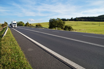 Asphalt road in a rural landscape. The arriving white truck.