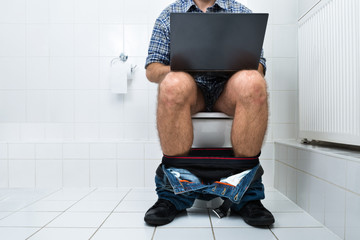 Man In Toilet Using Laptop - obrazy, fototapety, plakaty