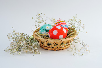 Easter eggs in a basket with hay on a white background