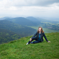 Naklejka na ściany i meble Girl sitting on the slope of volcano in Auvergne