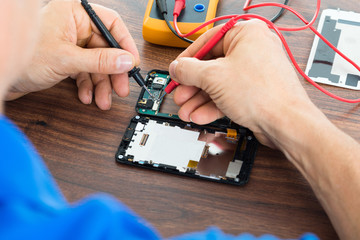 Technician Repairing Cellphone With Multimeter