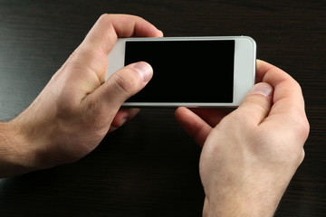 Hands holding smart mobile phone on wooden table background