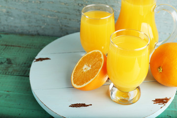 Glass of orange juice with slices on color wooden background