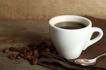 Cup of coffee with beans on rustic wooden background