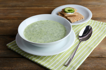 Cucumber soup in bowl on rustic wooden table background