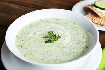 Cucumber soup in bowl on rustic wooden table background