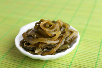Seaweed in white bowl on bamboo mat background