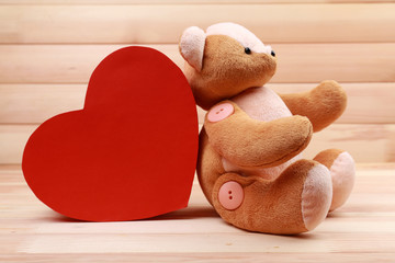 Teddy Bear with red heart on wooden background