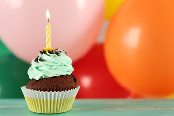 Delicious birthday cupcake on table on bright background